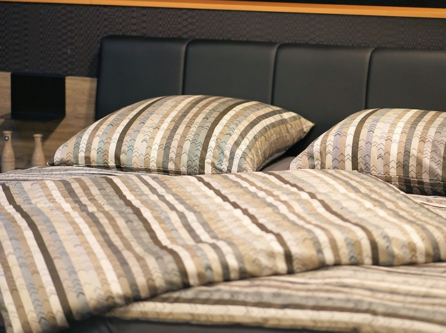 Manželská posteľ s hnedým obliečkami a koženým čelom.jpg