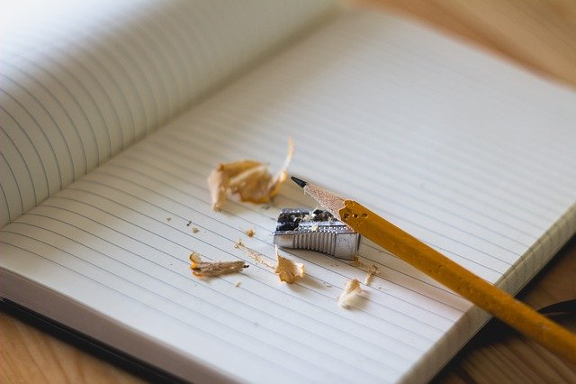 Ostrúhaná ceruzka a strúhadlo na poznámkovom zošite s riadkami